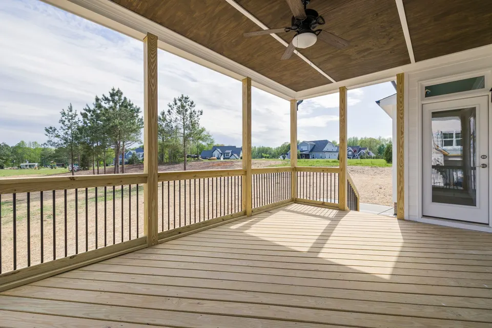 Covered wooden back deck with a railing and a white glass door opening onto the yard